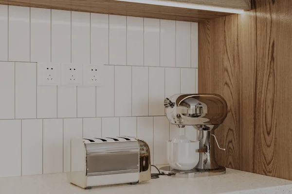 An electric toaster and coffee maker on the island in the kitchen.
