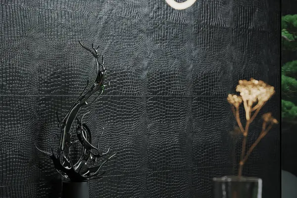There is a black sculpture standing in the dining room against a black background.
