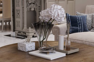 Bir sehpanın yakın çekimi, içinde çiçekler, mumlar ve oturma odasında bir kitap var.