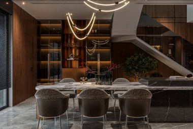 Adaya bağlı mermer bir masa, şık sandalyeler ve ortam aydınlatması olan zarif bir yemek salonu.