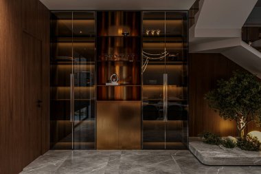 Modern dubleks evin içinde koyu ahşap dolaplar, cam kapılar ve taş zemini olan bir giriş var..