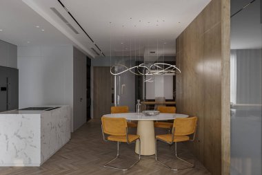 İçinde sandalyeler ve ada tezgahı olan bir yemek masası olan modern minimalist bir daire..