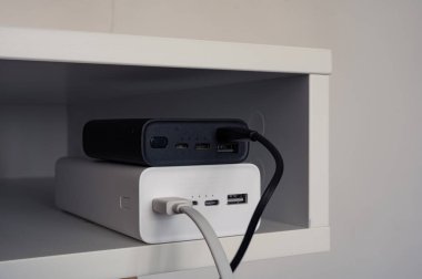 Siyah güç bankasının altındaki beyaz enerji bankası. Siyah beyaz kablolu şarj aletleri. Masada.