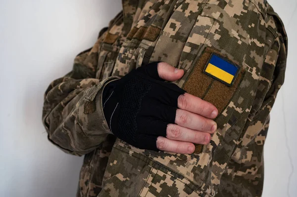 Ukrainian soldier in military pixel unform with banner of flag of Ukraine on shoulder and arm in black glove