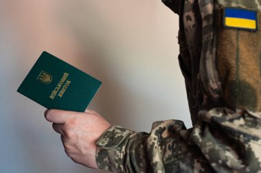 Taktik kıyafetli asker askeri kimlik belgelerini elinde tutuyor. Ukrayna piksel üniforması