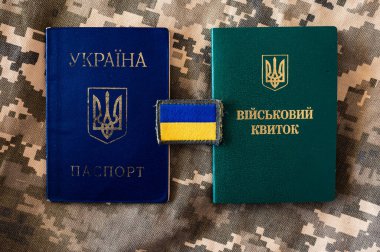 Ukrayna pasaportu ve Ukrayna bayrağı taşıyan askeri kimlik kartı. Piksel kamuflaj arkaplanı