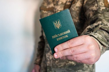 Kamuflajlı asker askeri kimlik belgelerini sol elinde tutuyor. Ukrayna piksel üniforması