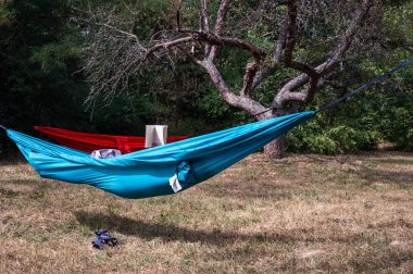Mavi hamak, kırmızı hamak ve içinde biri kitap okuyor. Turizm, kamp, donanım teması