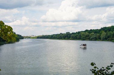 Nehirde beyaz bir yat, yemyeşil ormanlar kıyıda, gökyüzünde ve arka planda uzak bir kasabada. Manzara, güzel, kart manzaralı, duvar kağıdı, Vinnytsia, Ukrayna, Pivdennyi Buh