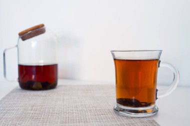 Bardakta siyah çay ve beyaz arka planda yeni demlenmiş cam çaydanlık.