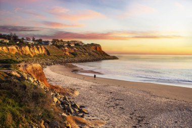 Sahilde gün batımı manzarası. Sahilde gezinen bir insan.