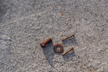 Paslı civata ve vidalar beton zemine saçılmıştı. beyaz arkaplan