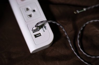 Siyah USB kablo yüklü beyaz güç soketi kahverengi arka planda izole