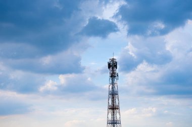 Antenler ve elektrik direkleri Bulutların önünde güneş batarken sırtında çivit bir göbek var.