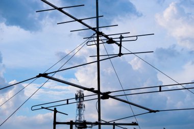 Antenler ve elektrik direkleri Bulutların önünde güneş batarken sırtında çivit bir göbek var.