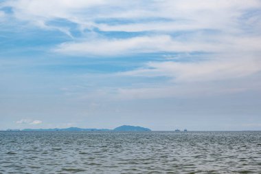 Hafif esintili deniz manzaraydı, ve uzakta, denizin ortasında yüksek binalar ve dağlar vardı..