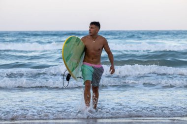 Sahilde sörf tahtası olan bir adam.