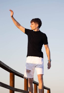 Genç adam yürüyor ve el sallıyor.