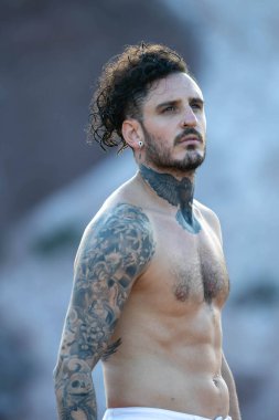 Dövmeli, piercingsiz, üstsüz bir adam.