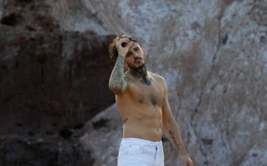 Dövmeli, piercingsiz, üstsüz bir adam.