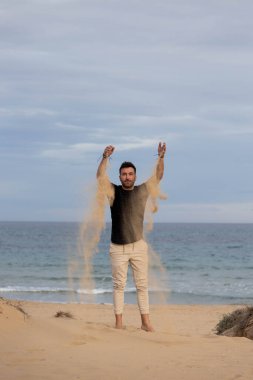 Çıplak ayaklı adam kumsalda kumla oynuyor.