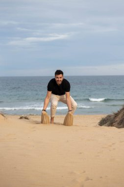 Çıplak ayaklı adam kumsalda kumla oynuyor.