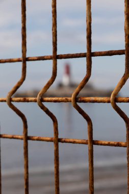 Lighthouse in the sea with a fence clipart