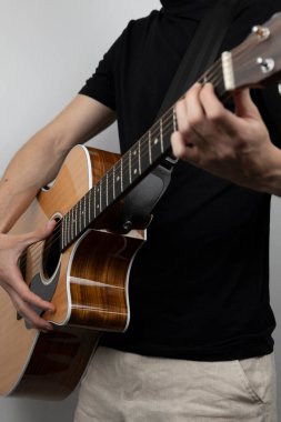 Siyah tişörtlü bir adam fotoğraf stüdyosunda gitar çalıyor.