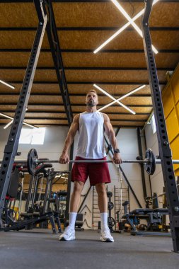 Spor salonunda bar egzersizi yapan bir adam.