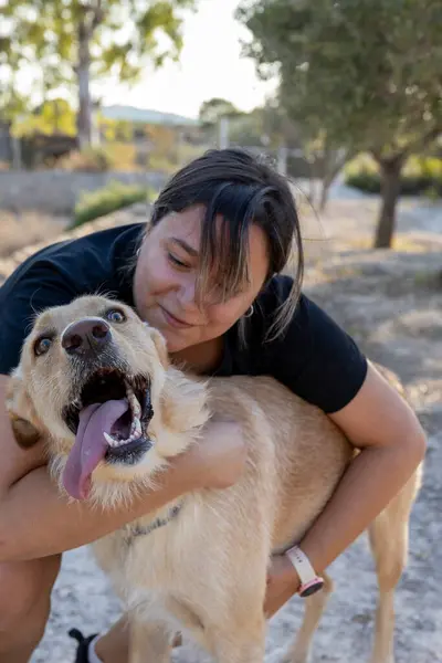 stock image Girl hugging a big brown dog with a big tongue.