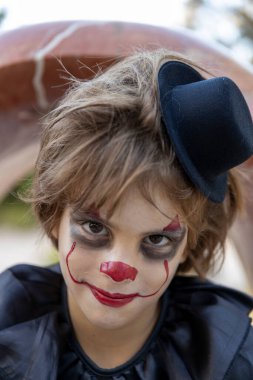 Cadılar Bayramı için korkunç bir palyaço kılığında gülümseyen bir çocuğun portresi.