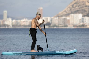 Adam köpekle sörf yapıyor..