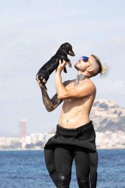 Denizin kenarında bir köpeği öpen adam..