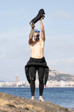 Köpeği denizin kenarında tutan adam..