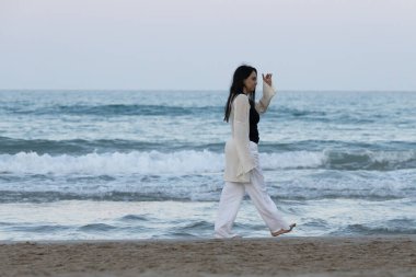 Gün batımında sahilde yürüyen bir kız..