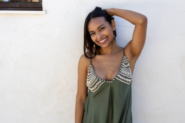 Beyaz duvarda yeşil elbise giyen Latin bir model..