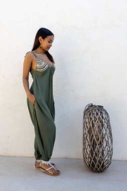 Beyaz duvarda yeşil elbise giyen Latin bir model..