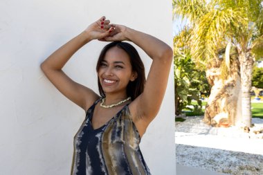 Beyaz bir duvara karşı yazlık elbiseyle poz veren Kolombiyalı bir model.