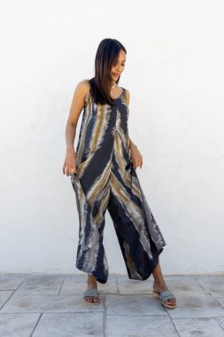 Beyaz bir duvara karşı yazlık elbiseyle poz veren Kolombiyalı bir model.