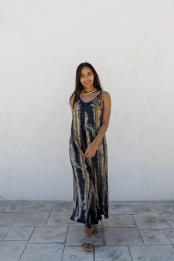 Beyaz bir duvara karşı yazlık elbiseyle poz veren Kolombiyalı bir model.