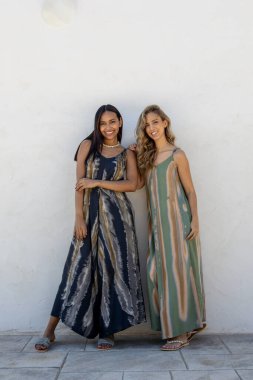 Beyaz bir duvarda yaz kıyafetleri içinde poz veren mankenler..