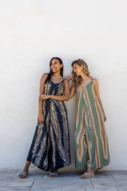 Beyaz bir duvarda yaz kıyafetleri içinde poz veren mankenler..