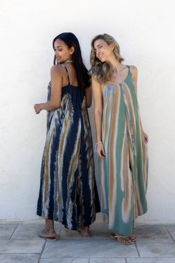 Beyaz bir duvarda yaz kıyafetleri içinde poz veren mankenler..