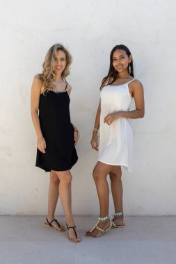 Siyah beyaz yaz kıyafetleri giyen sarışın ve bronz tenli mankenler..