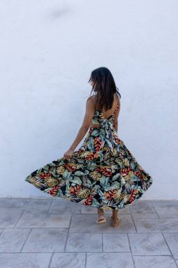 Beyaz arka planda esmer bir kadın. Yazlık elbise giyiyor..