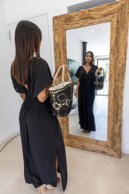 Birls aynanın önünde yazlık elbiseler giyiyor..