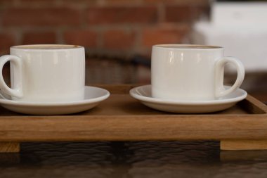 Kafedeki ahşap tepside iki beyaz seramik kahve.