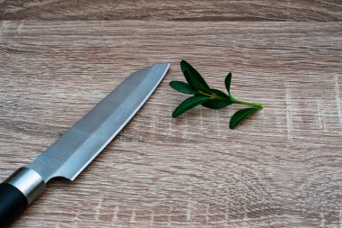 Tahtada taze yeşil yapraklar ve mutfak bıçağı var.