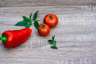 still life of fresh two tomatoes, one red pepper, mint for the salad on a wooden background, close up. Top view. Place for text or logo. Healthy eating concept.