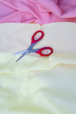 Dikiş ve dikiş aksesuarları, sarı kumaşta kırmızı makas.